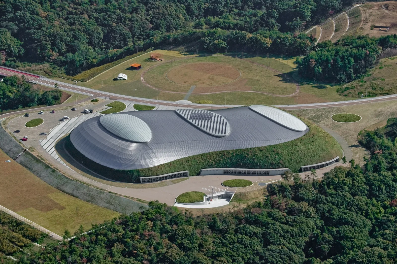 Aerial photo of the Bourbon Beans Dome in Miki City with its park, running track and parking in the surrounding green landscape